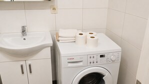 Ein kleiner Waschraum mit Waschmaschine, Waschbecken und Schrank.