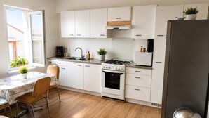 Eine moderne Küche mit weißen Schränken, einem Gasherd, einer Spüle und einem Kühlschrank.