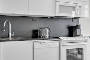A modern kitchen with a dishwasher, a coffee maker, and a microwave.