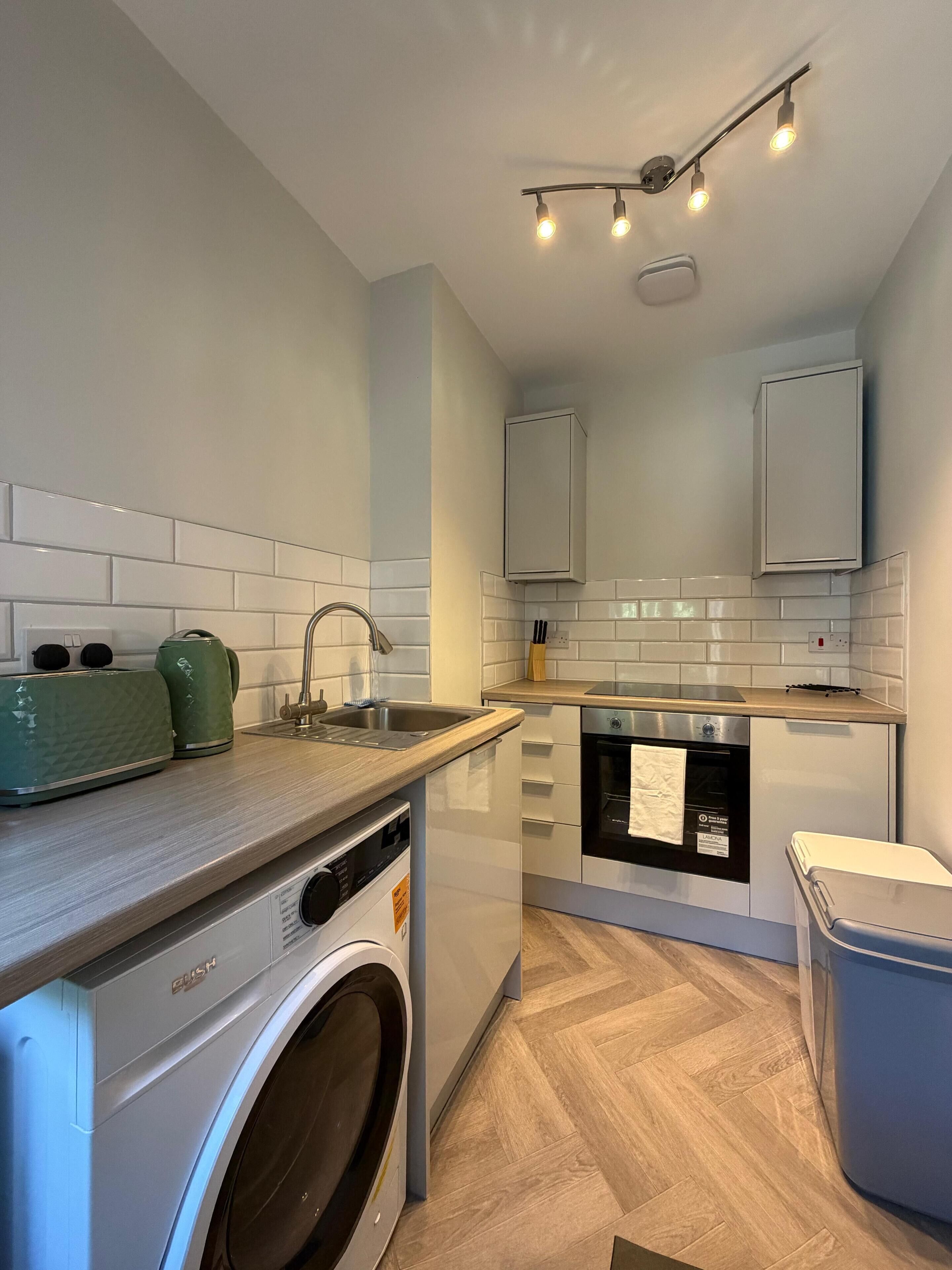 A compact kitchen with a washing machine, a dishwasher, and a small countertop.