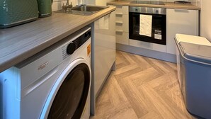 Une cuisine compacte équipée d’un lave-linge, d’un lave-vaisselle et d’un petit plan de travail.