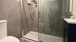 Une salle de bain moderne équipée d’une douche, de toilettes et d’un meuble-lavabo.
