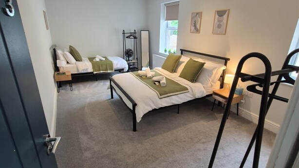 Une chambre avec deux lits, un ventilateur de plafond, une fenêtre et une porte.