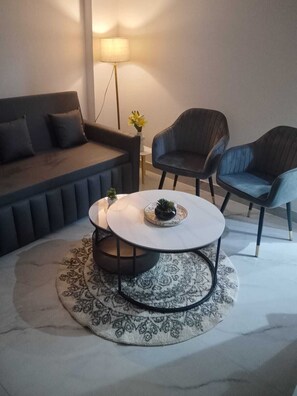 Uma sala de estar moderna com um sofá, duas poltronas, uma mesa de centro e um abajur.