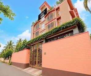 A multi-story building with a gated entrance, a sign indicating it is a collection and one-off serviced property, and a number 16 sign on the gate. - Classic Cherry City Cottage (Guwahati)