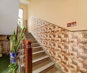 A staircase with a stone wall on one side and a wooden handrail. - Classic Cherry City Cottage (Guwahati)