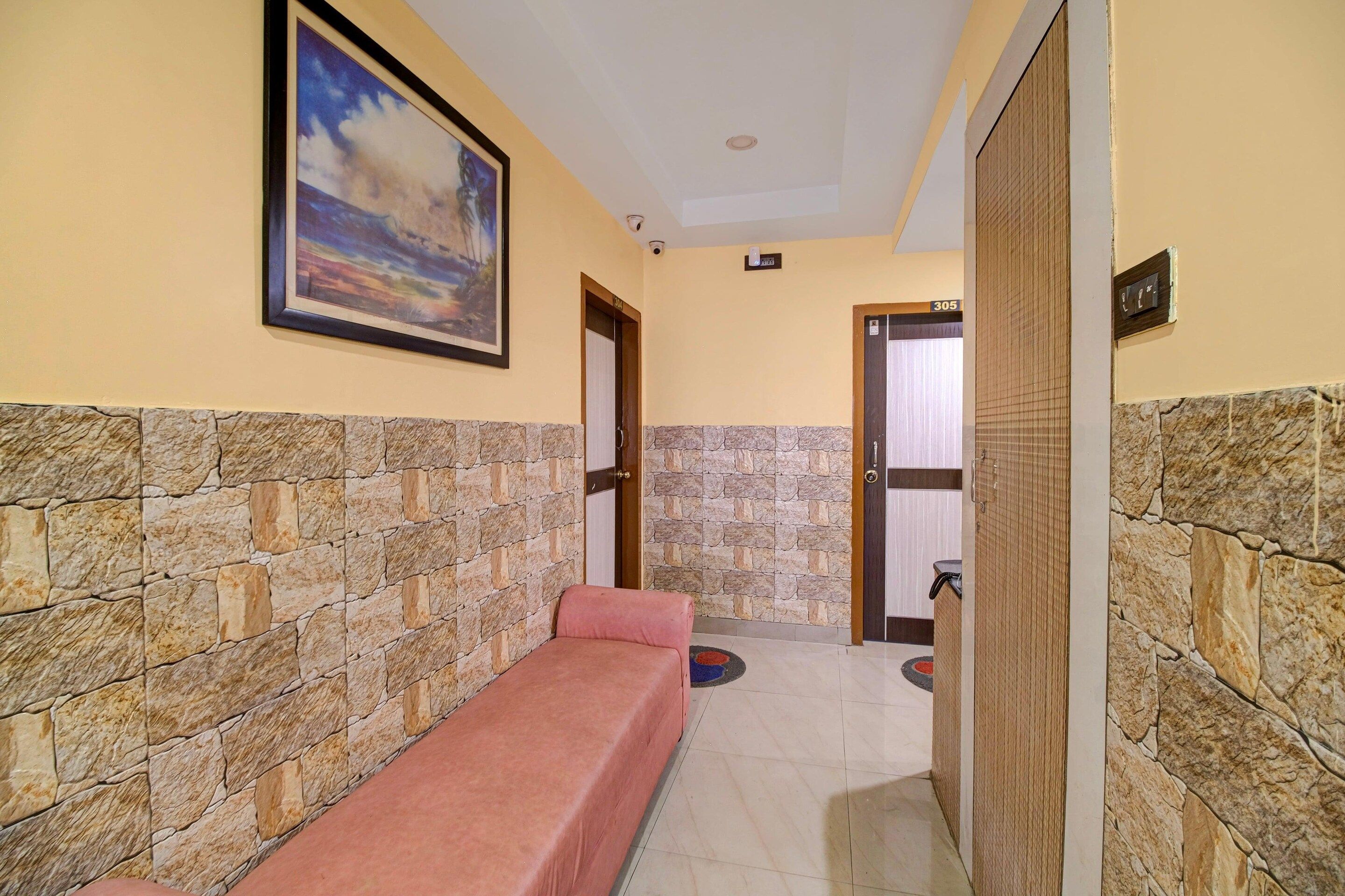 A hallway with a stone wall, a bench, a door, and a framed picture on the wall.