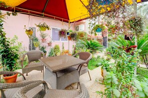 An outdoor seating area with wicker furniture and hanging plants. - Classic Cherry City Cottage (Guwahati)