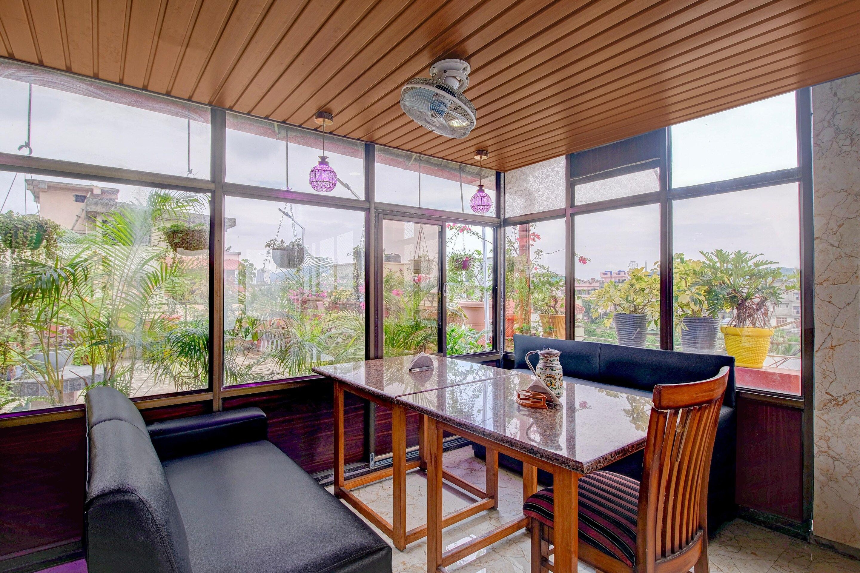 A room with a glass wall, a wooden ceiling, a table with chairs, and a bench.