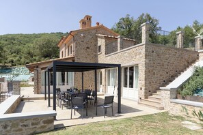 Ein Steingebäude mit einer überdachten Veranda und Sitzgelegenheiten im Freien.