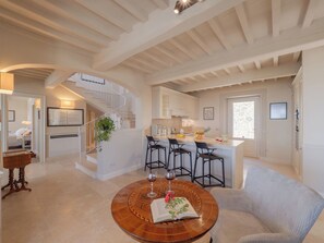 A spacious living area with a staircase, a kitchen, and a dining area with a round wooden table. - Wonderful private villa for 8 guests with private pool, WIFI, A/C, patio and panoramic view (Cortona)