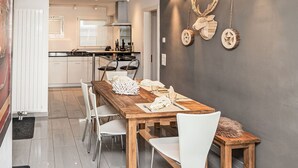 Una cucina moderna con pensili bianchi, un tavolo da pranzo in legno e due sedie bianche.