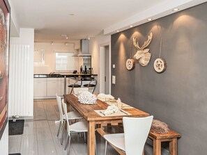 Eine moderne Küche mit weißen Schränken, einem Holzesstisch und zwei weißen Stühlen.