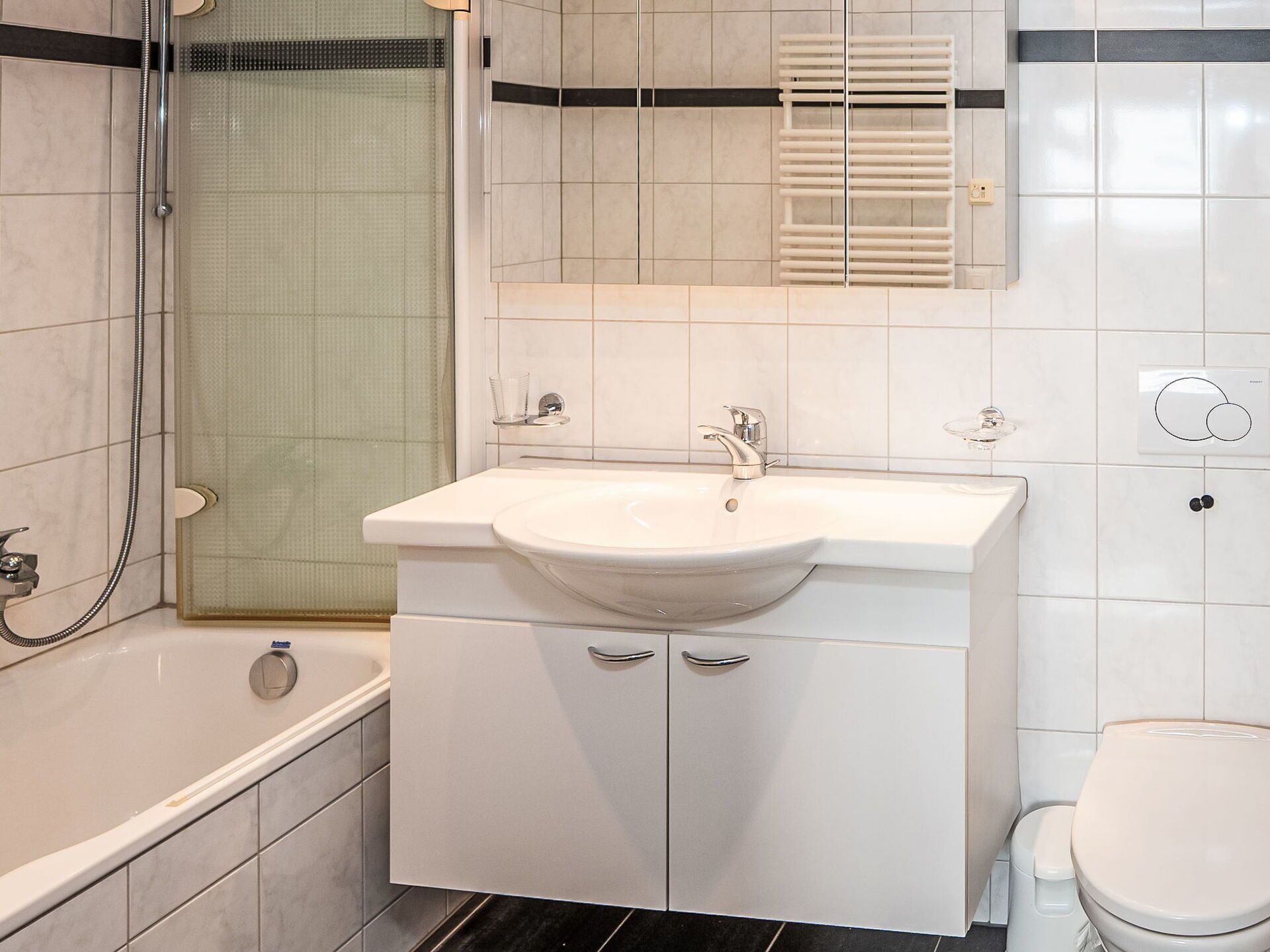A bathroom with a bathtub, a sink with a mirror above it, and a toilet.