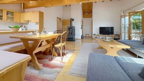Ein großzügiger Wohnbereich mit einem Holzessttisch, einer Couch und einem Fernseher.
