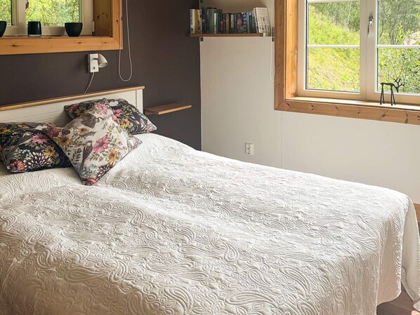 A bedroom with a bed, pillows, a bedside table, a window, and a bookshelf. - 9 Person Holiday Home in Tanndalen (Tanndalen)