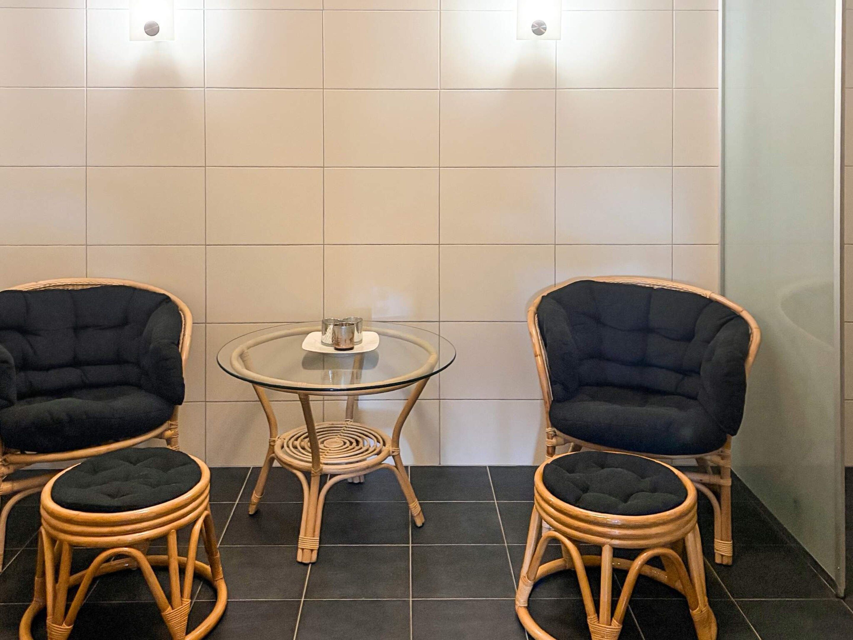 A room with two wicker chairs and a glass table with a coaster set.