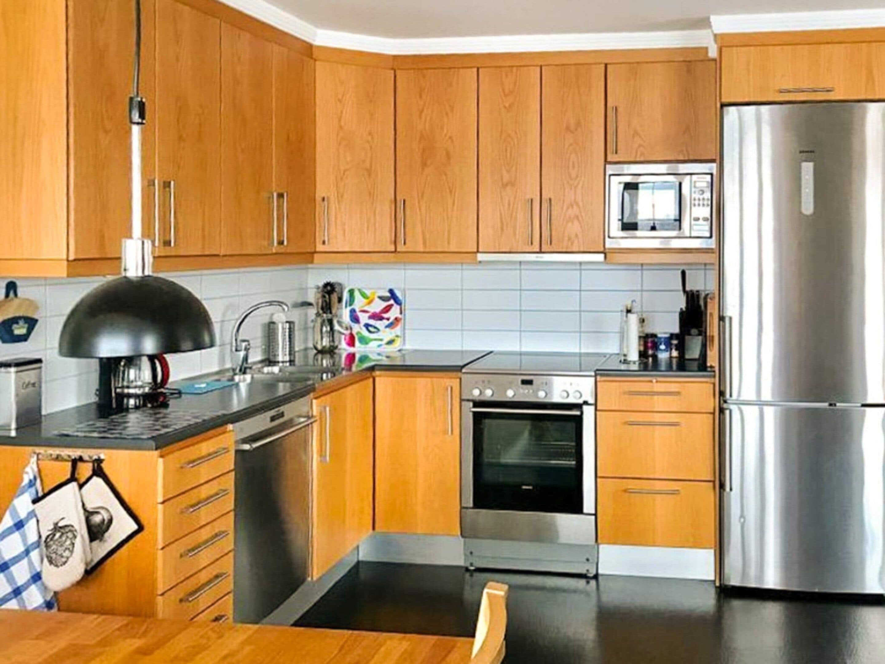 Una cocina moderna con armarios de madera, un refrigerador de acero inoxidable, un horno y un microondas.