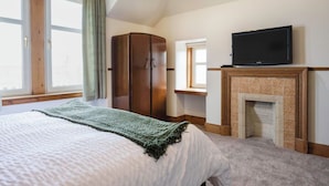 A bedroom with a bed, a wardrobe, a television, and a fireplace. - Beautiful  villa for 8 guests with WIFI and TV (Lossiemouth)