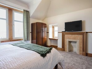Ein Schlafzimmer mit Bett, Kleiderschrank, Fernseher und Kamin.