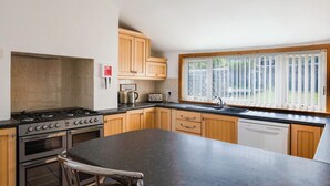 A kitchen with a gas stove, oven, coffee bar sign, and a window with blinds. - Beautiful  villa for 8 guests with WIFI and TV (Lossiemouth)