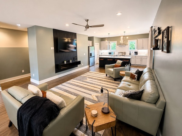 Ein modernes Wohnzimmer mit einer Couch, einem Couchtisch und einem an der Wand befestigten Fernseher.