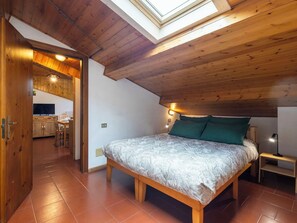 Quarto com claraboia, teto de madeira e cama com manta estampada.