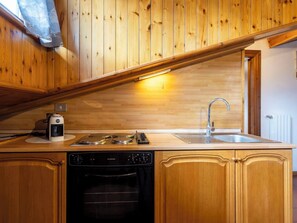 Eine Küche mit Holzausstattung, einem eingebauten Backofen, einer Kaffeemaschine und einem Spülbecken.