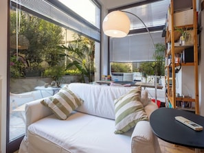 Ein modernes Wohnzimmer mit einem weißen Sofa, gestreiften Kissen, einem runden schwarzen Tisch und einem Bücherregal.