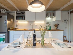 Eine moderne Küche mit weißen Schränken, einer Holzausziehtafel und einem Essbereich, der für eine Mahlzeit gedeckt ist.