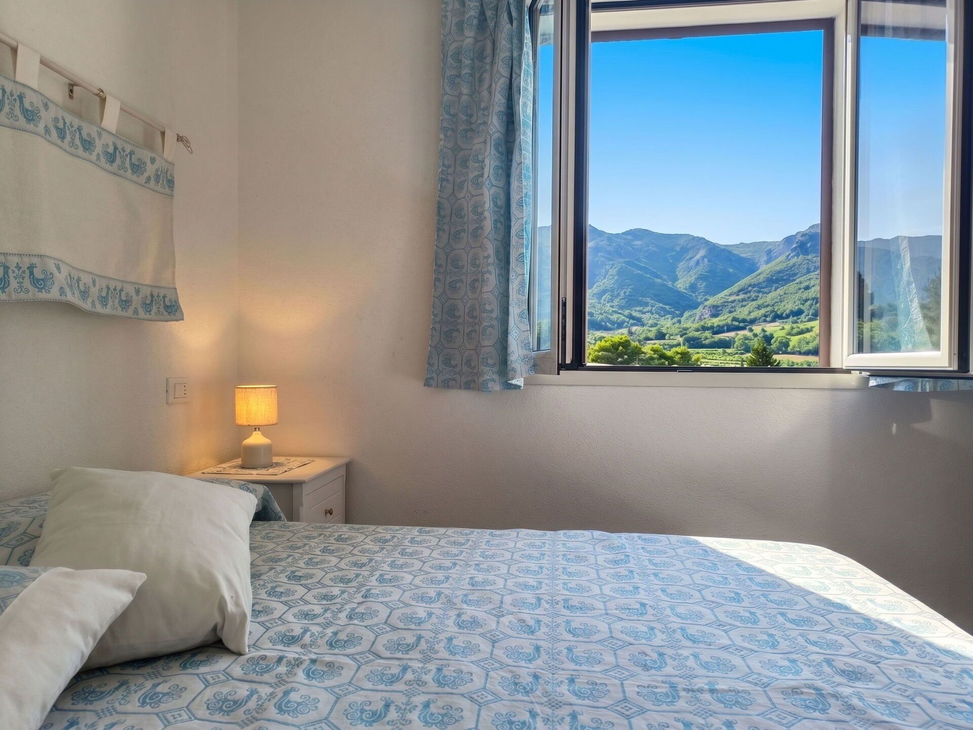 Une chambre à coucher avec un lit, une table de chevet avec une lampe et une fenêtre donnant sur la montagne.