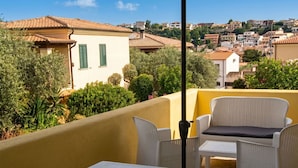 Una terrazza con mobili da esterno, vista su una cittadina collinare e un edificio con persiane verdi.
