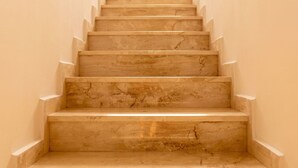 Una scala di marmo con corrimano che sale in linea retta.