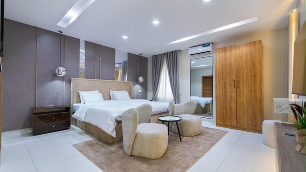 Une chambre moderne avec un grand lit, des tables de chevet, une petite table ronde et une armoire.