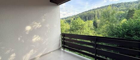 En balkon med udsigt over en skovklædt bakke.