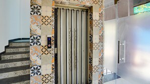 A modern elevator with a patterned wall, a metal handrail, and a control panel. - Classic Gomti Nagar Station (Lucknow)