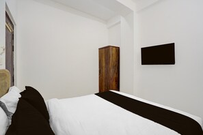 A bedroom with a bed, a wardrobe, and a flat-screen TV mounted on the wall. - Classic Gomti Nagar Station (Lucknow)