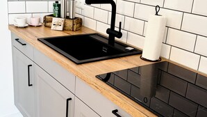 A kitchen with a black sink, wooden countertop, and grey cabinets.