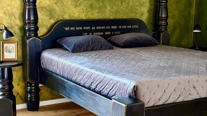 A bed with a dark headboard, two side tables, and a green wall.