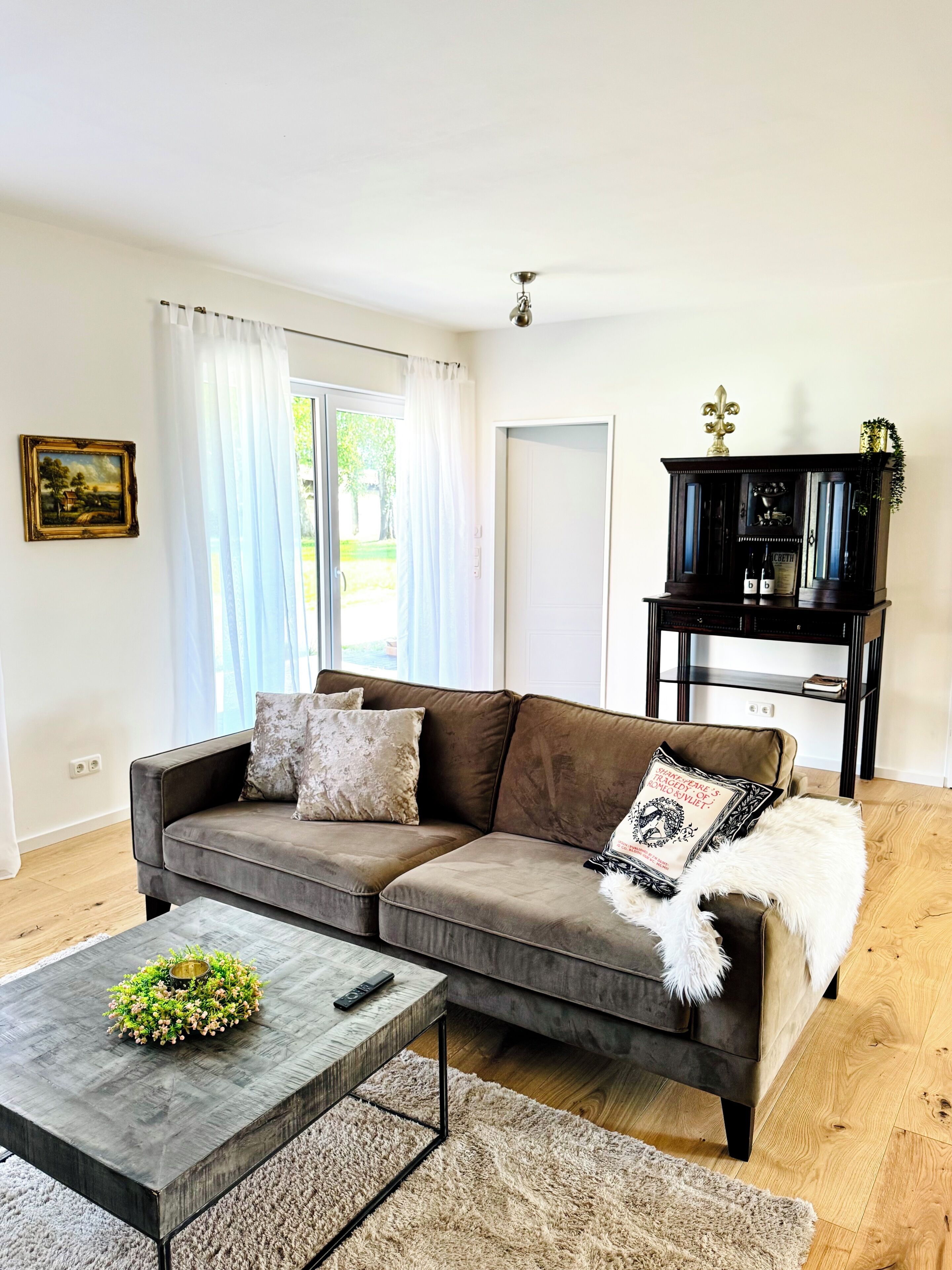 Una sala de estar con sofá, una mesa de centro con control remoto, chimenea y una puerta que da al exterior.