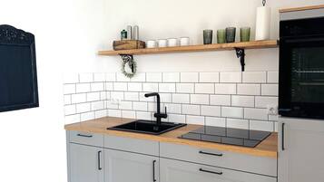 A kitchen with white cabinets, a wooden countertop, a black sink, and a built-in oven.