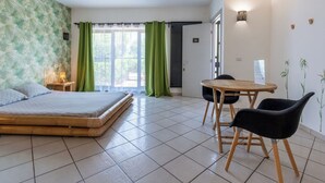 Um quarto com uma cama, uma mesa de jantar com cadeiras, uma mesinha de cabeceira com abajur e uma porta com a inscrição 'Ape'.
