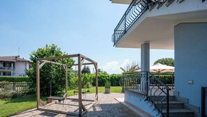 Um pátio com balanço, escada e um prédio com varanda.