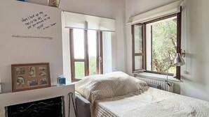 Una camera da letto con un letto, un termosifone, una finestra e una parete con una foto incorniciata.