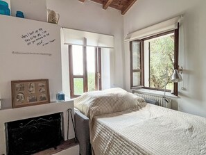 Ein Schlafzimmer mit einem Bett, einem Heizkörper, einem Fenster und einer Wand mit einem gerahmten Foto.