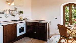 Una cucina con mobili scuri in legno, un piano cottura bianco e una finestra che si affaccia sul verde.