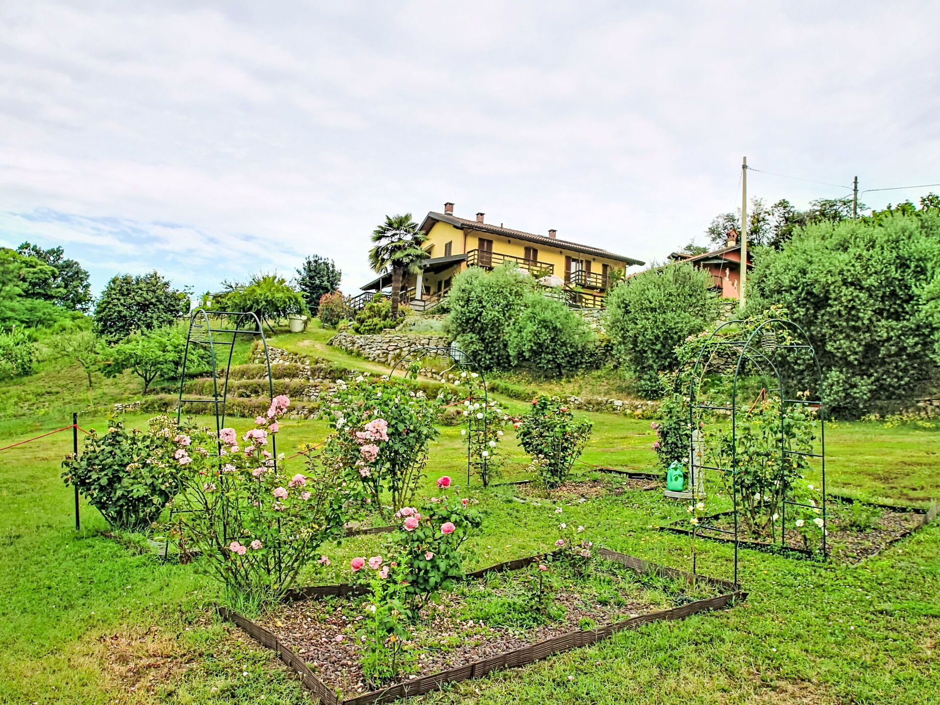 Ein Haus mit Garten, einschließlich Rosenbüschen und einer Steinmauer.