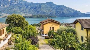 Un quartier résidentiel avec un bâtiment jaune, une allée pavée et une vue sur un lac, avec des montagnes en arrière-plan.