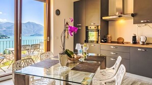 Une cuisine moderne avec vue sur les montagnes, un coin repas avec une table en verre et un balcon équipé de chaises.