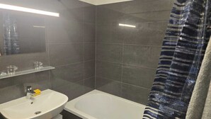 A bathroom with a white sink, mirror, and bathtub. - LUFT Apartment in Kritzendorf/Klosterneuburg near Vienna, with parking (Klosterneuburg)